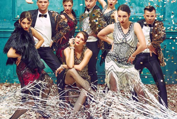 The studio shot of group of retro dancers posing at carnival tinsel. Concept of cabaret, luxury party and jazz